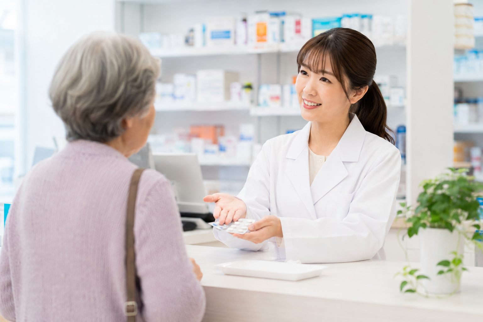 薬局のカウンターで、薬剤師が患者さまに薬の説明をしているイメージ